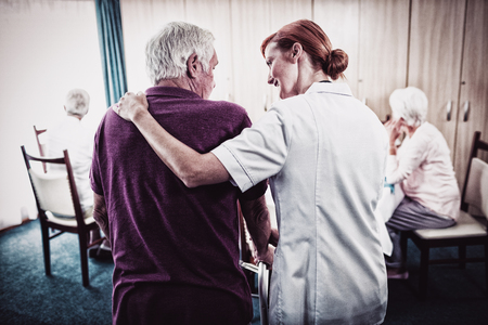 Nurse assisting a senior using a walker in the retirement houseの写真素材
