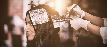 Hairdresser dyeing hair of her client at a salonの写真素材