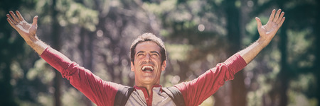 Man smiling and throwing up arms on the woodの写真素材