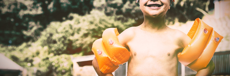 Portrait of boy wearing arm band standing at poolside