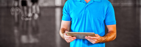 Portrait of sports teacher using digital tablet in basketball court at school gymの写真素材