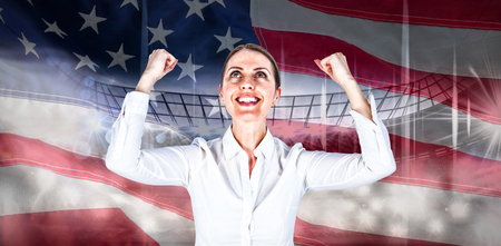 Successful businesswoman with clenched fists looking up against close-up of an american flagの写真素材