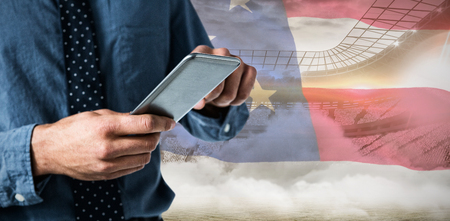 Mid-section of business man using smartphone against close-up of an american flagの写真素材