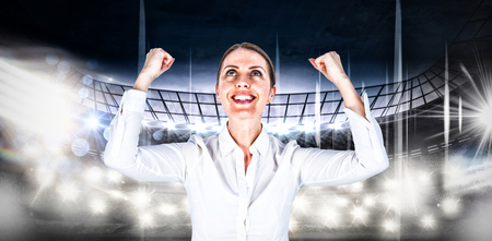 Successful businesswoman with clenched fists looking up against american football arenaの写真素材