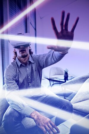 Gray and purple background against male executive using laptop and virtual reality headset in...