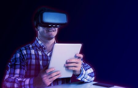 Male use virtual reality headset with digital tablet against gradient