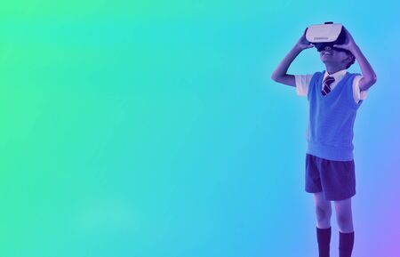 Full length of school boy wearing virtual reality headset against turquoise and purple backgroundの写真素材
