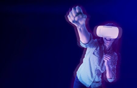 Woman gesturing while using virtual reality headset against gradient