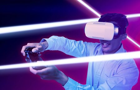 Creative businessman wearing VR glasses while video game against turquoise and purple background
