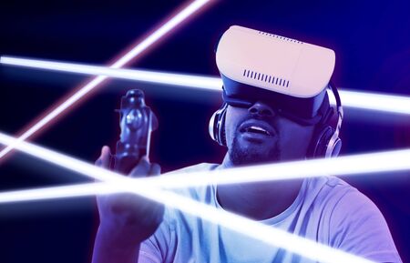 Man using virtual reality headset and playing video game against gradient