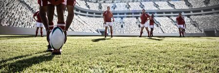 Rugby player putting ball on the field. against rugby stadiumの写真素材
