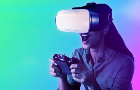 Woman playing video game with virtual reality headset against turquoise and purple backgroundの写真素材