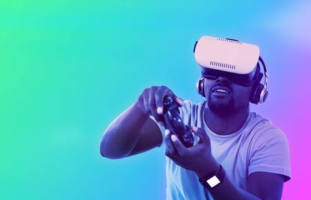 Man using virtual reality headset and playing video game against turquoise and purple background