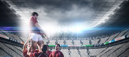 Male rugby players playing rugby in the ground against stadium against skyの写真素材