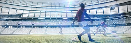Rugby player kicking the ball to teammates on field. against rugby stadium at dawn