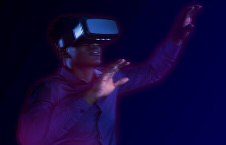 Happy man using VR headset against gradientの写真素材