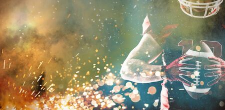 Young American football player standing with helmet and ball against white backgroundの写真素材