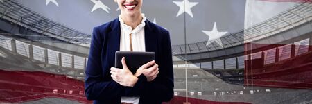 Portrait of smiling businesswoman holding tablet computer against close-up of an american flagの写真素材