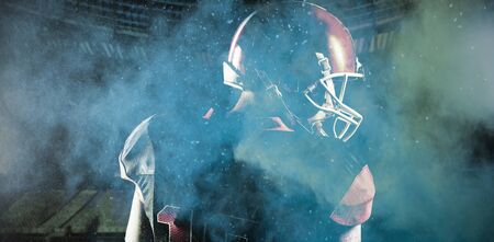 American football player in helmet looking off to the side against splashing of yellow color powderの写真素材