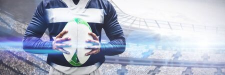 Strong Rugby Player against rugby ball on pitchの写真素材