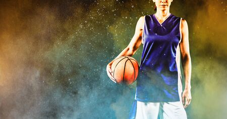 Tough female basketball player against splashing of yellow color powderの写真素材