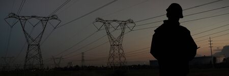 Architect writing notes on clipboard against the evening electricity pylon silhouette