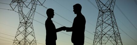 Silhouettes shaking hands against the evening electricity pylon silhouette