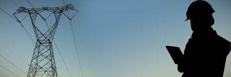 Female architect using digital tablet against the evening electricity pylon silhouette