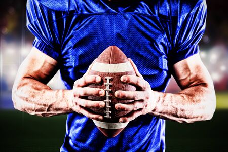 American football player against view of a blurred sports arenaの写真素材