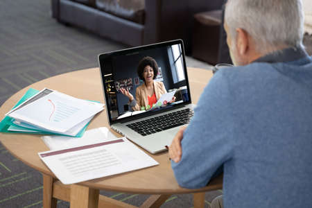 Caucasian man in office having video call with female colleague displayed on laptop screen. social...