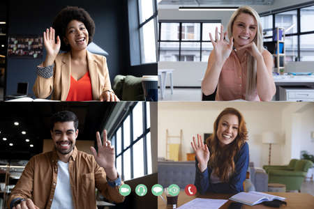 Diverse businesswomen and businessman waving on computer screen during video call. social distancing...