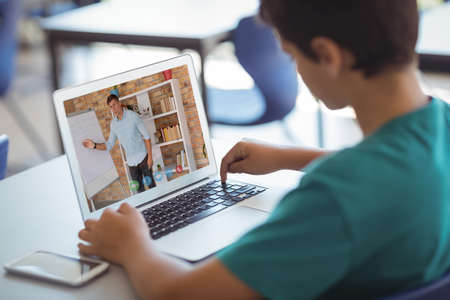 Caucasian schoolboy using laptop on video call with male teacher. Online education staying at home...
