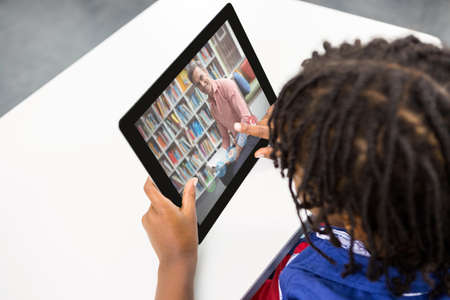 Mixed race schoolboy using digital tablet on video call with male teacher. Online education staying at home in self isolation during quarantine lockdown.の写真素材