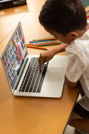 Mixed race schoolboy using laptop on video call with male teacher. Online education staying at home in self isolation during quarantine lockdown.の写真素材