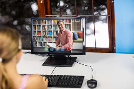 Female student having a video call with male teacher on computer at school. distance learning online education conceptの写真素材
