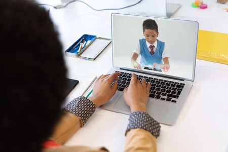 Female teacher having a video call with male student on laptop at school. distance learning online education conceptの写真素材