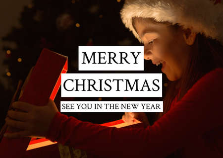 Merry christmas see you in the new year text over happy girl opening present in background. christmas greetings, celebration and festivity concept digitally generated image.の写真素材