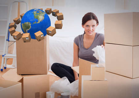 Composition of woman unpacking in new home with cardboard boxes and globe. moving house, global shipment and delivery concept digitally generated image.の写真素材