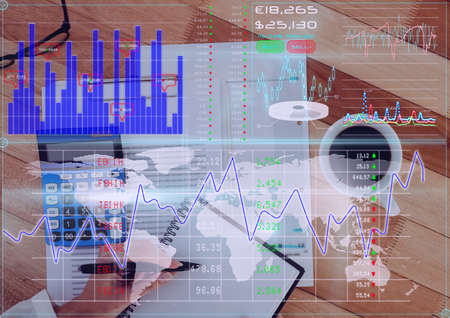 Financial data processing against person writing notes and office equipment on desk. global finance...