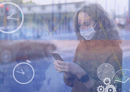 Digital clocks and financial data processing against woman wearing face mask using smartphone. global finance and covid-19 pandemic conceptの写真素材