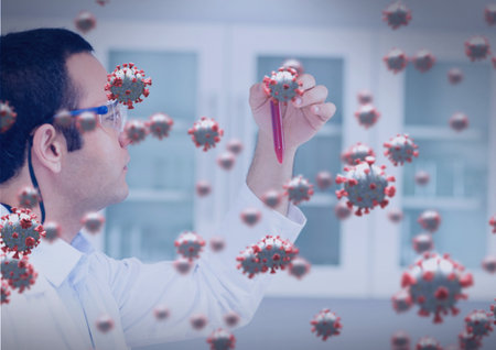 Composition of covid 19 cells over male scientist holding pipette with red liquid in laboratory. global coronavirus pandemic and health concept digitally generated image.の写真素材
