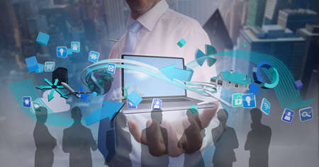 Composition of digital icons over businessman holding laptop and silhouettes of business people....