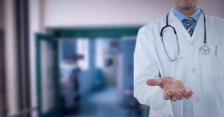 Mid section of male doctor with cupped han standing at hospital. healthcare and professionalism concept standingの写真素材