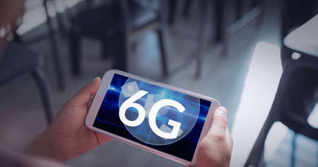 Composition of the word 6g over a person holding a smartphone in background. global technology,...