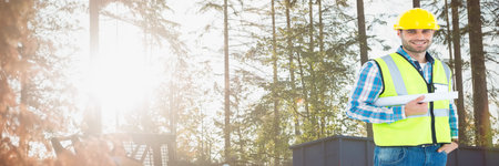 Smiling caucasian male engineer holding a plan against natural background, construction concept. digitally generated image.の写真素材