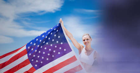 Composition of happy sports woman holding american flag over blue sky. american patriotism,...