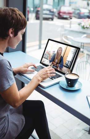 Businesswoman having a cup od coffee while using laptop in office