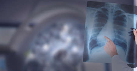 Mid section of doctor examining x-ray report against surgical light in background. healthcare and...