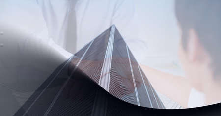 Mid section of businessmen shaking hands over tall buildings against grey technology background....