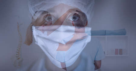 Caucasian female doctor wearing facemask against female doctor examining neck of male patient. medical healthcare during coronavirus covid 19 pandemic conceptの写真素材